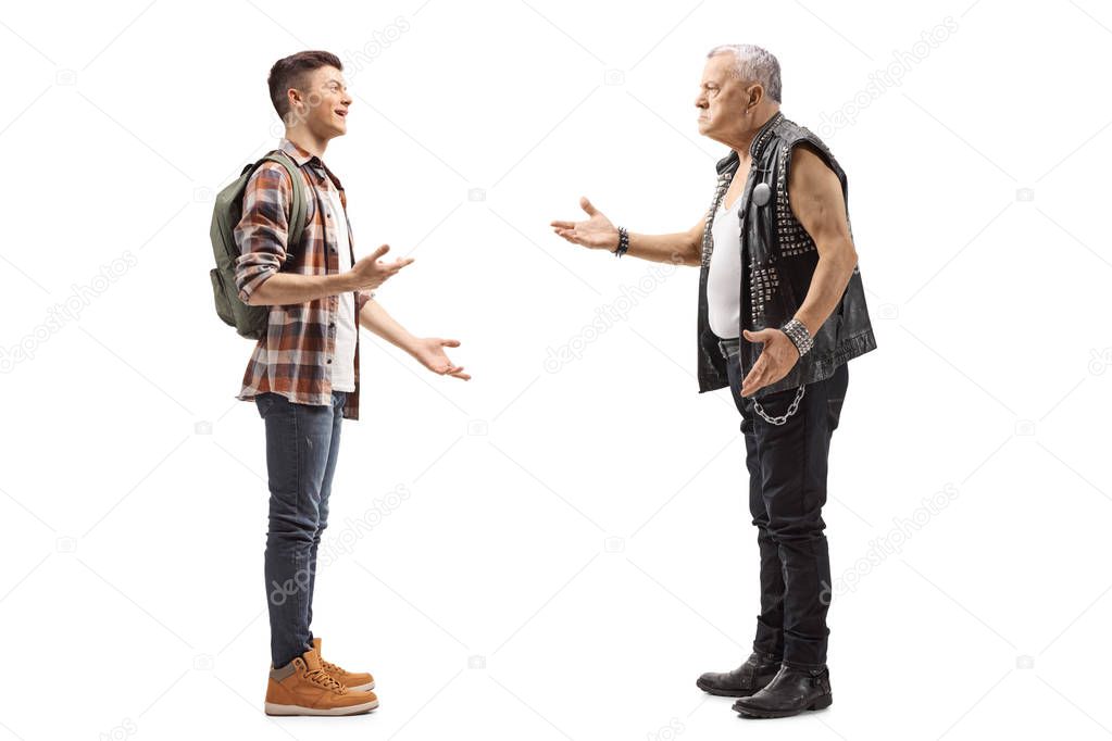 Full length profile shot of a male teenage student talking to a mature male punker in a leather vest isolated on white background