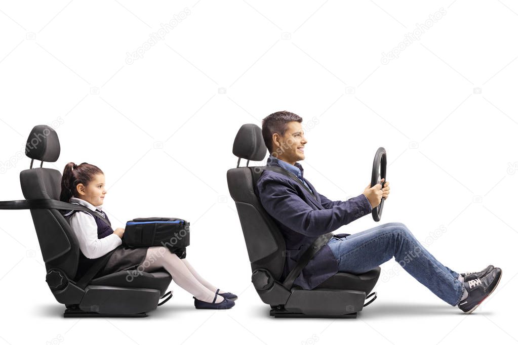 Full length profile shot of a young man in a car seat with a fastened seat belt holding a streering wheel and his daughter behind him isolated on white background