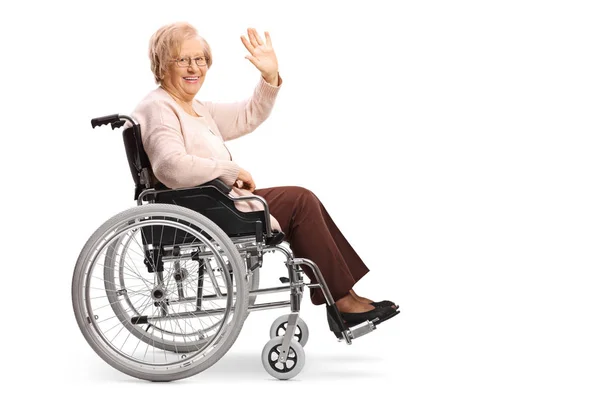 完全な長さのプロフィール撮影カメラに笑顔との分離の白い背景を振って車椅子で年上の女の — ストック写真