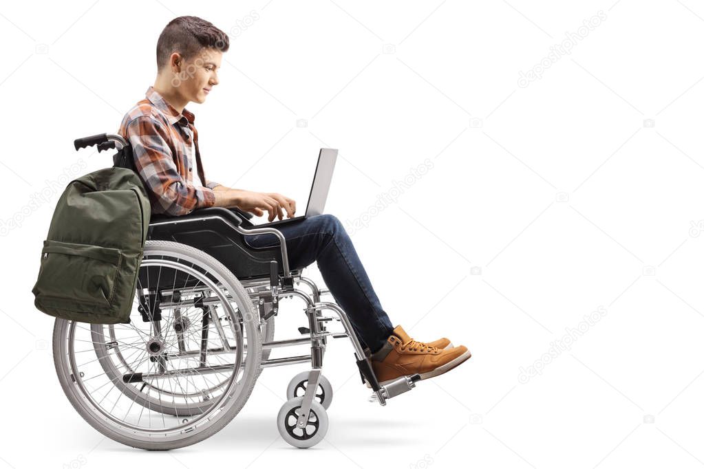 Full length profile shot of a disabled teenage male student working on a laptop in a wheelchair isolated on white background