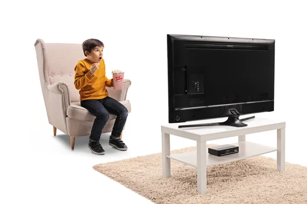 兴奋的小男孩在扶手椅与爆米花观看电视孤立在白色背景 — 图库照片