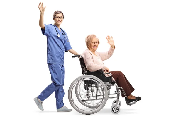 Полнометражный Снимок Молодой Медсестры Толкающей Пожилую Женщину Инвалидном Кресле Машущей — стоковое фото
