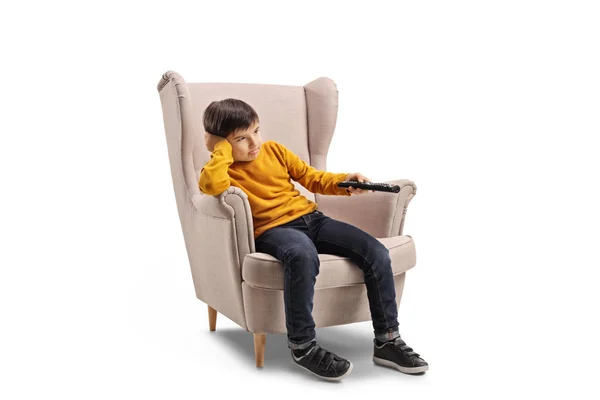 Foto Completa Niño Aburrido Sentado Sillón Sosteniendo Mando Distancia Aislado — Foto de Stock