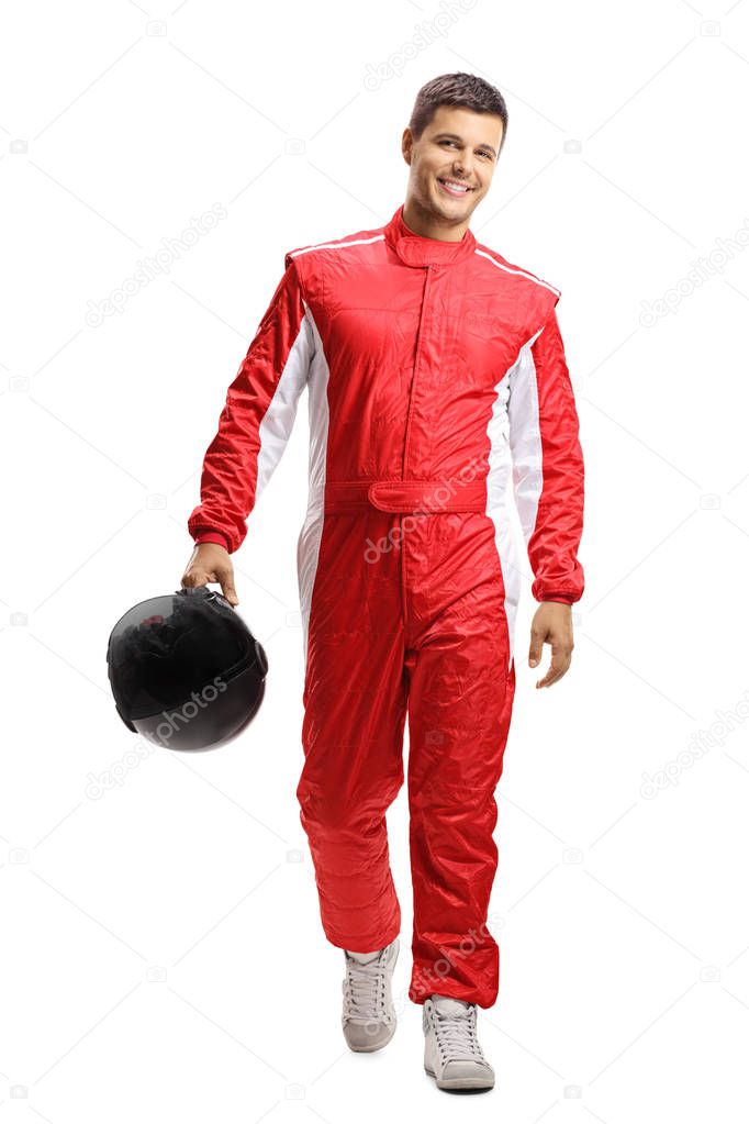 Full length portrait of a male car racer holding a helmet and walking towards the camera isolated on white background