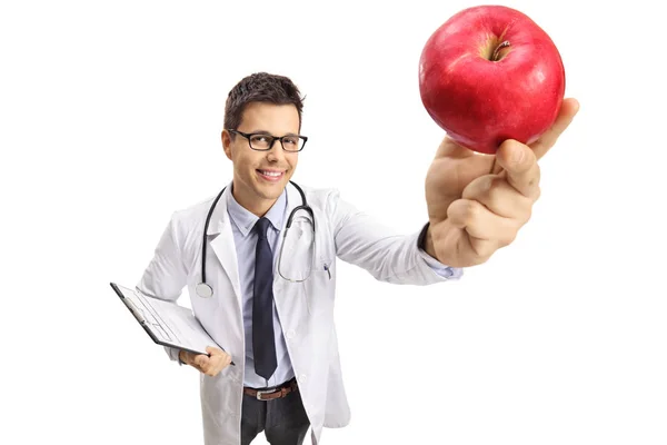 Sonriente Joven Médico Masculino Sosteniendo Una Manzana Roja Frente Cámara — Foto de Stock