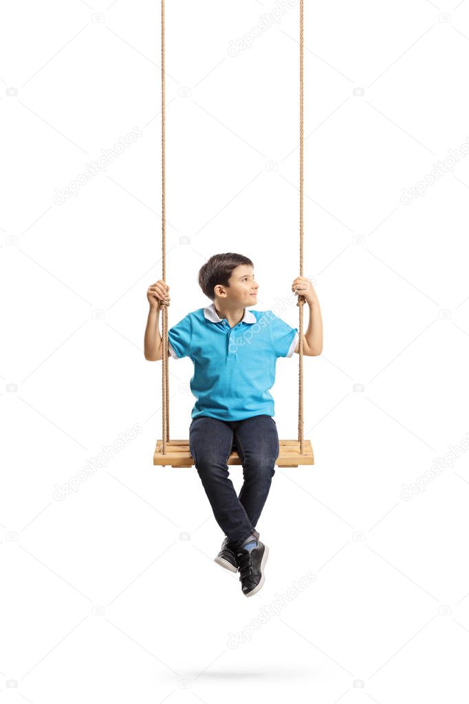 Full length portrait of a little boy sitting on a swing and looking to the side isolated on white background