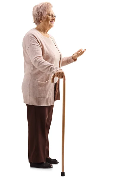 白い背景に孤立した手で杖とジェスチャーで立っている高齢女性の完全な長さのショット — ストック写真