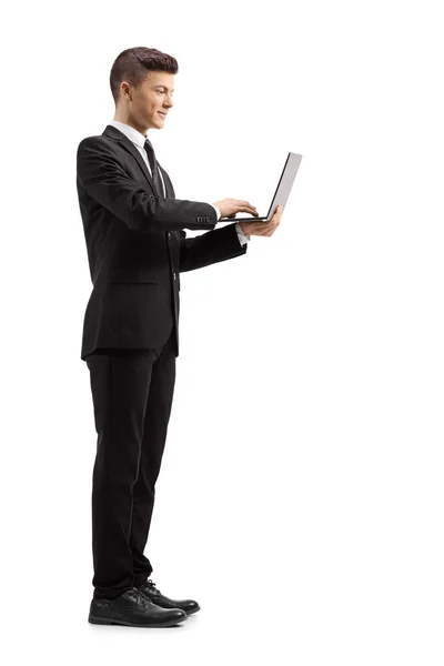 スーツの若い男の全長のショット Standind と白い背景に孤立したノートパソコンを使用して — ストック写真