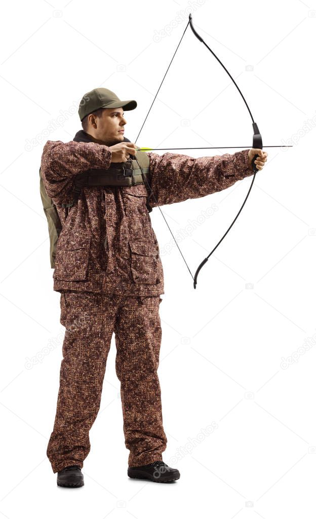 Full length shot of a hunter in a camuflage uniform aiming with a bow and arrow isolated on white background