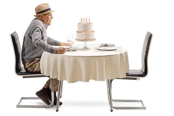 白い背景に分離されたレストランのテーブルにケーキの誕生日に興奮している年配の男性 — ストック写真