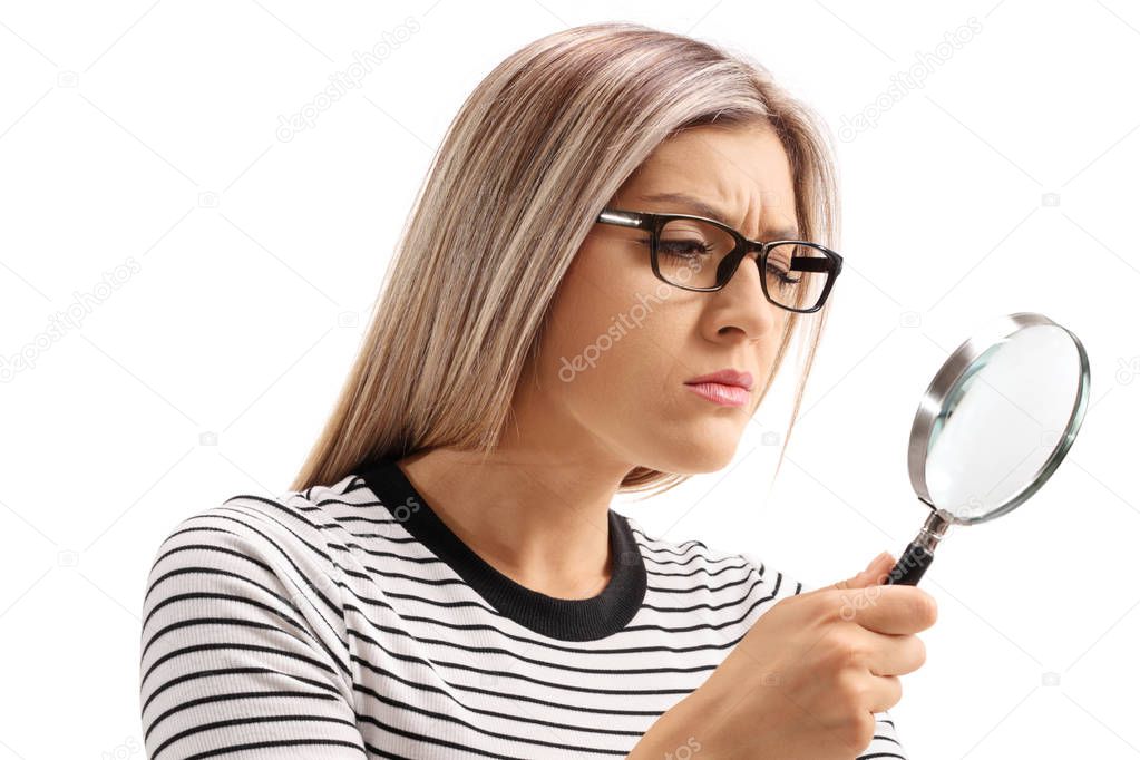 Young woman looking through a magnifying glass isolated on white background