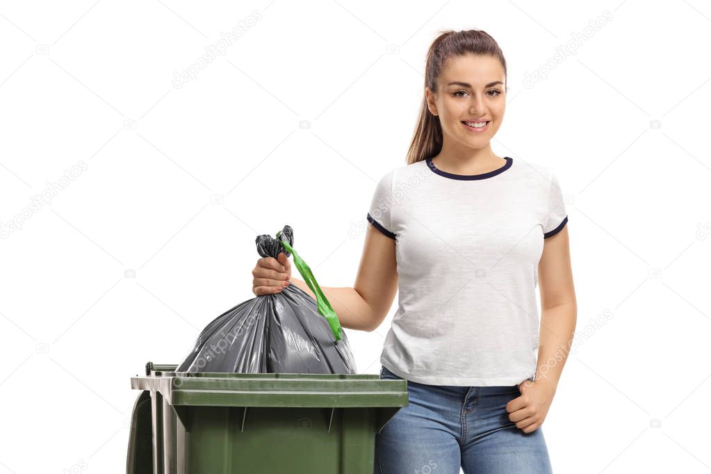 Young girl throwing a plastic garbage bag in a bin isolated on white background