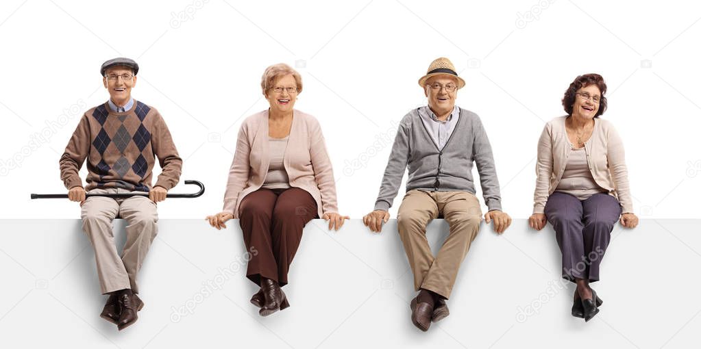 Full length portrait of two senior men and two senior women sitting on a white panel and posing isolated on white background