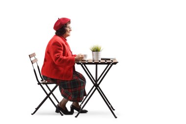Yaşlı kadın tek başına beyaz arka planda izole bir masada kahve içme