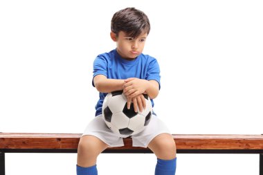 Beyaz arka planda izole ahşap bir tezgah üzerinde oturan bir futbol ile Sad küçük çocuk