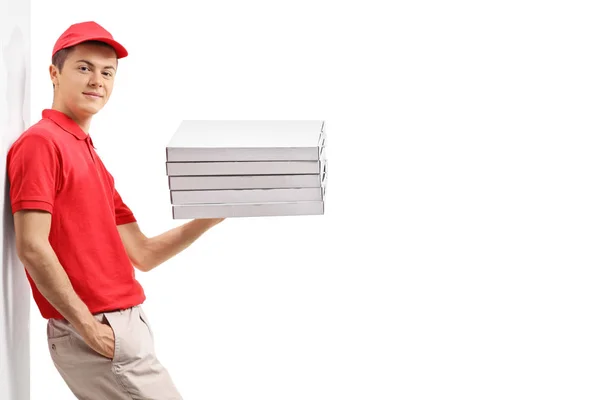 Pizza delivery guy with a stack of pizza boxes leaning against a wall isolated on white background