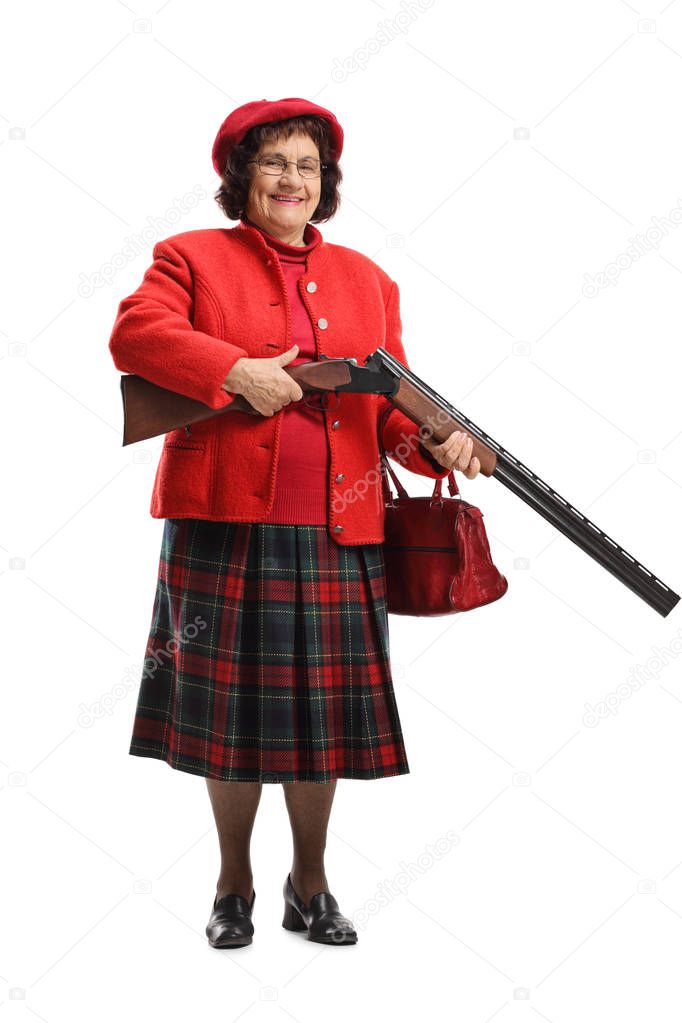 Full length portrait of an elderly lady charging a shotgun and smiling isolated on white background
