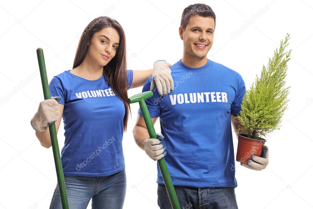 Young volunteers with tools and a plant posing isolated on white background