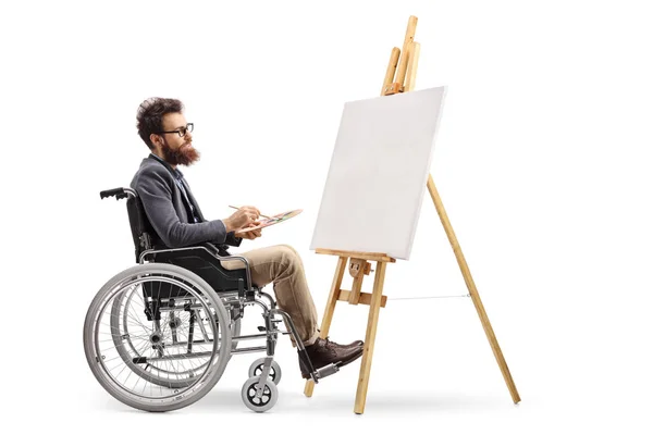 白い背景に孤立したキャンバス上の車椅子の絵の中の無効な男性アーティスト — ストック写真