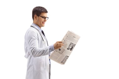 Young doctor standing and reading a newspaper isolated on white background clipart