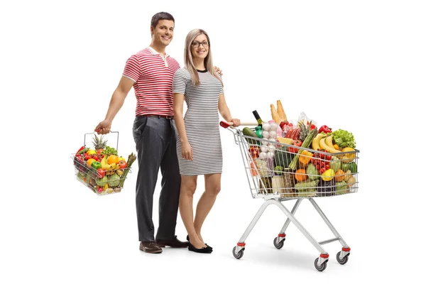 一对年轻夫妇 有一辆满载的购物车和一个白色背景的购物篮 — 图库照片