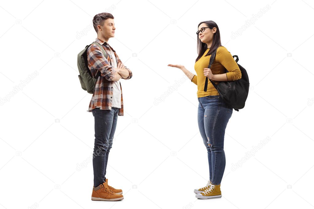 Full length profile shot of female student talking to a male student friend isolated on white background