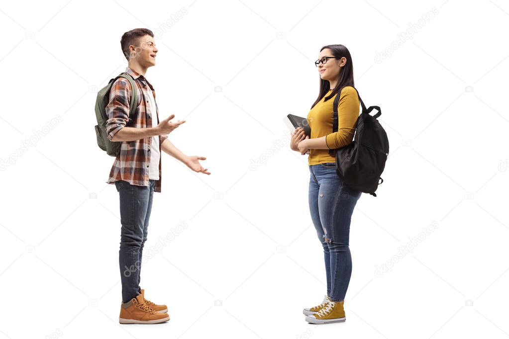 Full length profile shot of male and female students talking isolated on white background