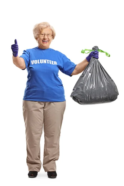 Femme âgée bénévole avec un sac à déchets donnant pouces vers le haut — Photo