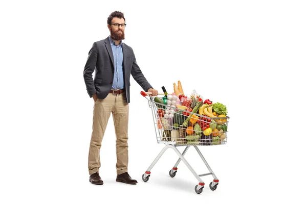Bärtiger Mann posiert mit beladenem Einkaufswagen — Stockfoto