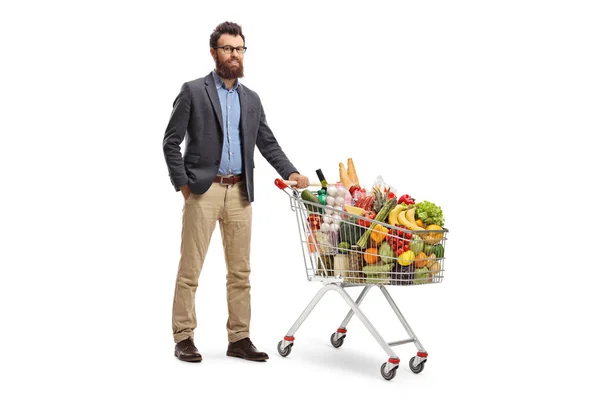 Uomo barbuto in posa con un carrello della spesa caricato — Foto Stock