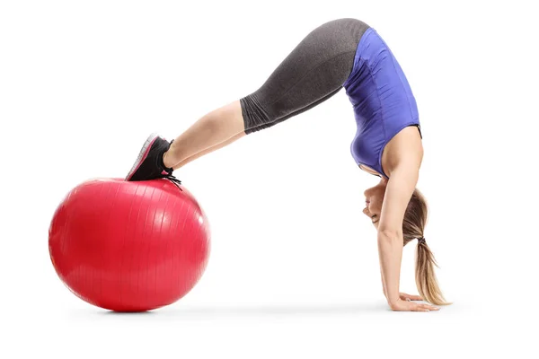 Ajuste a mulher jovem que equilibra em uma bola de aptidão e mãos praticantes — Fotografia de Stock