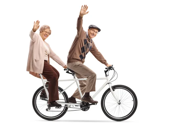 Senior couple riding a tandem bycicle and waving — Stock Photo, Image