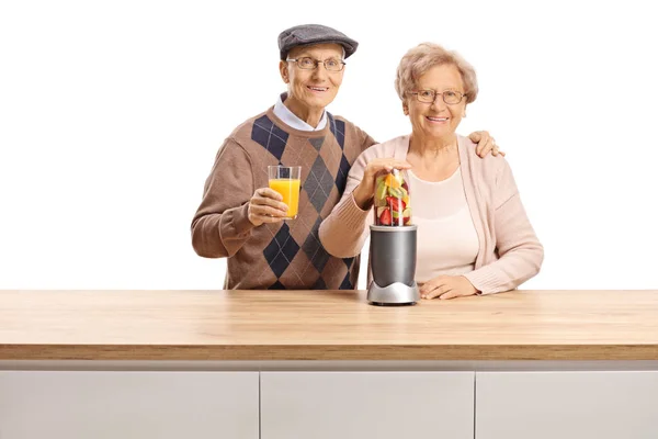 Senior couple posing with a fruit in a blender and a glass of he — Stock Photo, Image