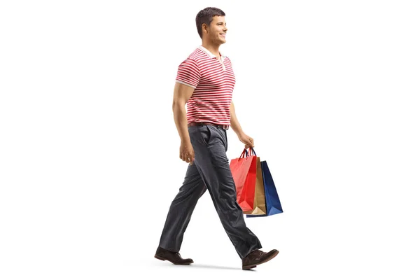 白い背景に隔離された買い物袋を持って歩く若いハンサムな男のフルレングスショット — ストック写真
