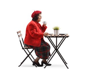 Yaşlı kadın bir kafede bir fincan kahve içiyor