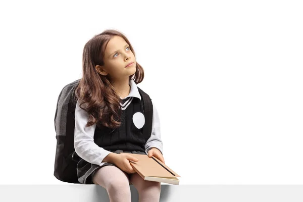 Pequena estudante segurando um livro e pensando — Fotografia de Stock