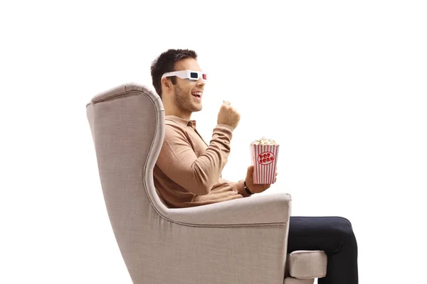 坐在扶手椅上的年轻人戴着3D眼镜 吃着白色背景的爆米花 — 图库照片
