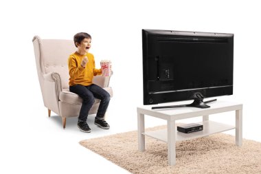 Patlamış mısır ile bir koltukta oturan bir çocuğun tam uzunlukta çekim, Tv izlerken ve beyaz arka plan üzerinde izole gülüyor