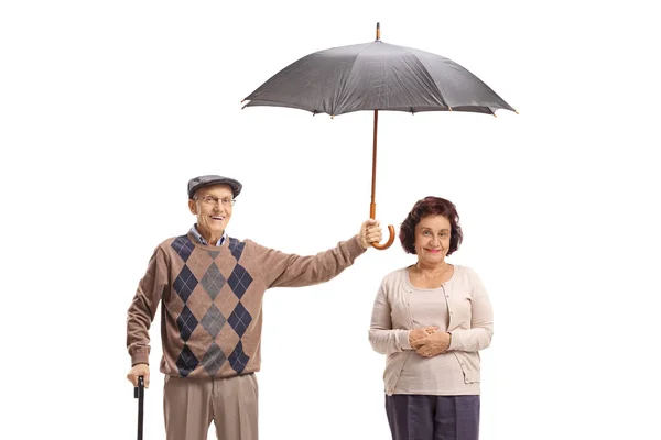 Un homme âgé tenant un parapluie au-dessus d'une dame âgée — Photo