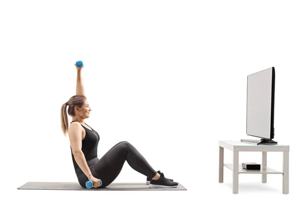 Mujer joven haciendo ejercicio frente a un televisor — Foto de Stock