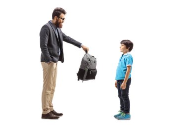 Bir babanın beyaz arka planda izole edilmiş oğluna sırt çantası verirken uzun bir çekim.