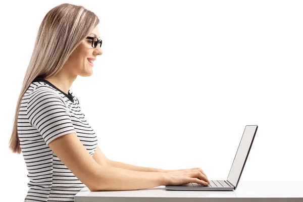 白い背景に隔離されたラップトップコンピュータに座って作業している若いブロンドの女性のプロフィールショット — ストック写真