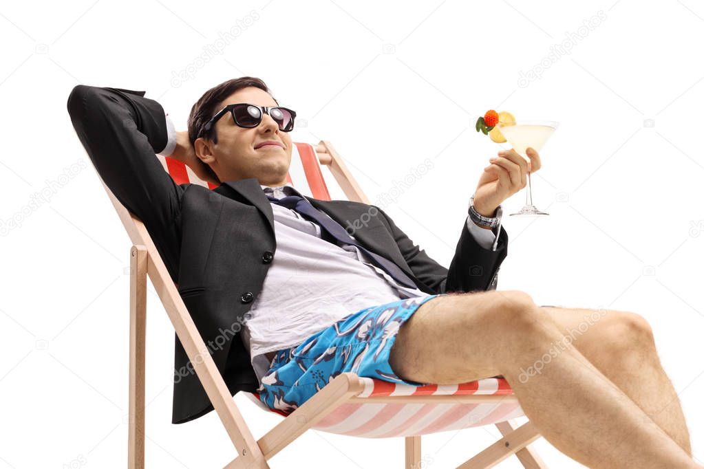 Businessman with a cocktail lying in a deck chair isolated on white background