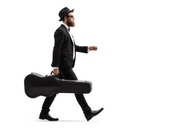 Beyaz arka plan üzerinde izole bir gitar kılıfı ile yürüyen bir erkek müzisyenin tam uzunlukta profil çekim