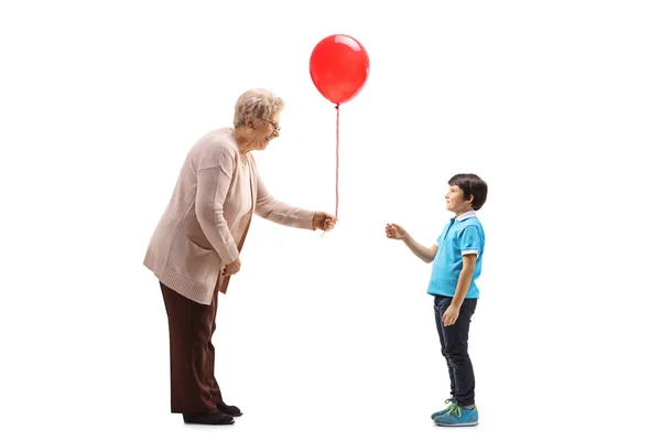 Farmor ger en röd ballong till ett barnbarn — Stockfoto