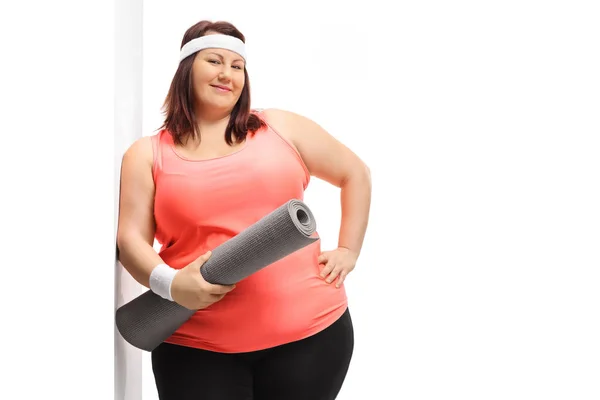 Young overweight woman with an exercise mat leaning against a wa — 스톡 사진