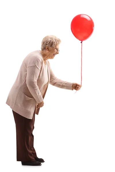 Ηλικιωμένη γυναίκα που κρατά ένα κόκκινο μπαλόνι — Φωτογραφία Αρχείου