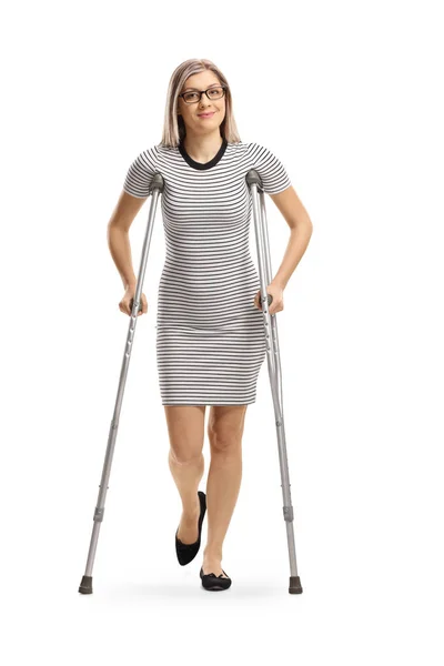 白い背景に隔離された松葉杖で歩いている負傷した脚を持つ若い女性の完全な長さの肖像画 — ストック写真