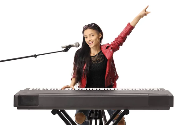 Mosolygós fiatal nő, aki játszik billentyűzetet és énekel egy micropho — Stock Fotó