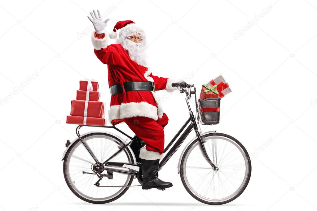 Full length shot of Santa Claus carrying presents on a bicycle and waving isolated on white background